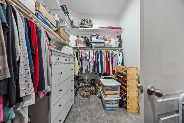 a view of walk in closet with clothes and shoes