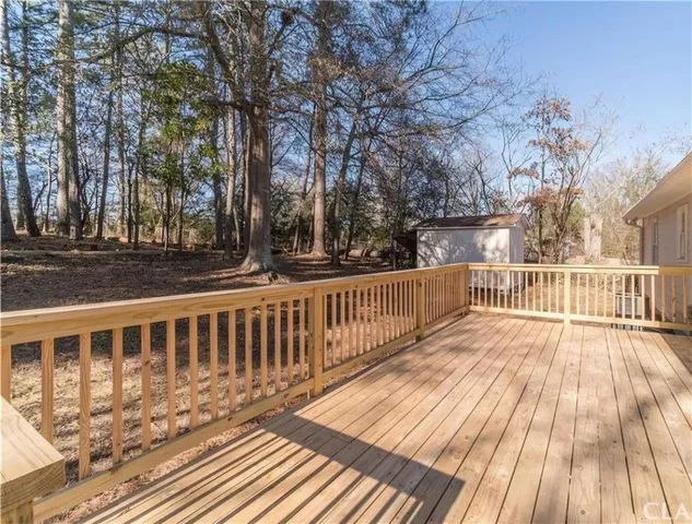 a view of deck with wooden floor and fence with a trees