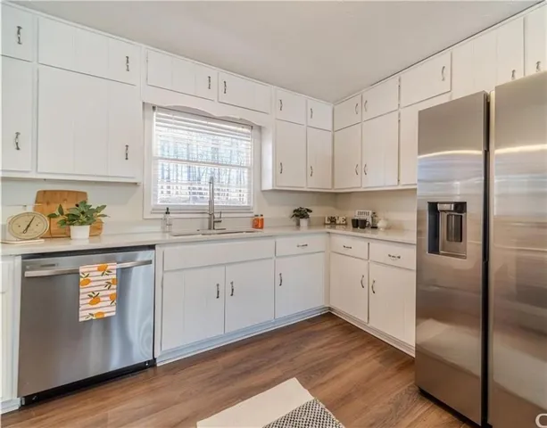 a kitchen with stainless steel appliances granite countertop a refrigerator sink and white cabinets