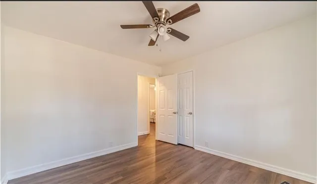 an empty room with wooden floor and ceiling fan