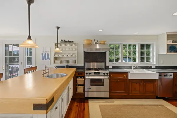 a kitchen with stainless steel appliances a stove a sink a counter top space and living room view
