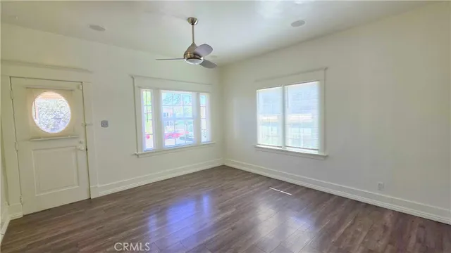 a view of an empty room with a window and wooden floor