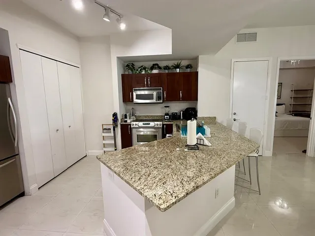 a kitchen with stainless steel appliances granite countertop a sink and a refrigerator