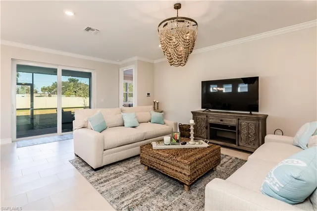 a living room with furniture a flat screen tv and a chandelier