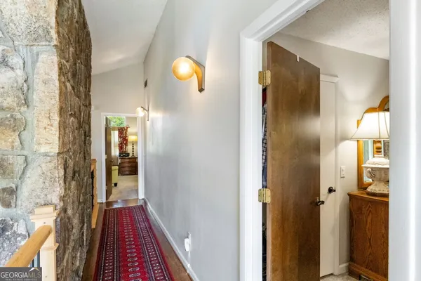 a view of a hallway with wooden floor and a bathroom