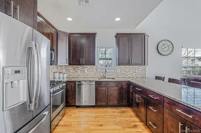 a kitchen with granite countertop a refrigerator and a stove top oven