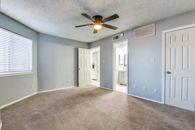a view of an empty room with a ceiling fan and window