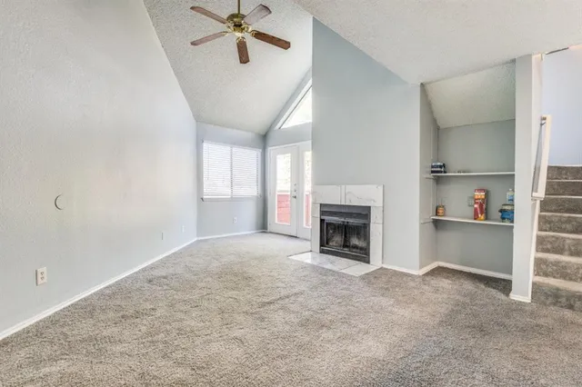 a view of a livingroom with a fireplace a ceiling fan and windows
