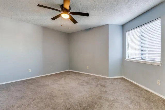 an empty room with a window and a fan
