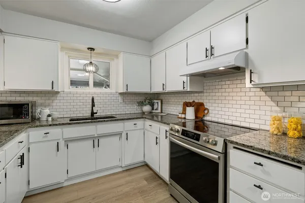 a kitchen with stainless steel appliances granite countertop white cabinets a sink and dishwasher