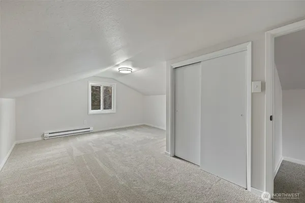 a view of an empty room with window and cabinet area