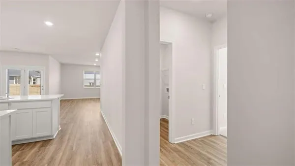 a view of a hallway with wooden floor and a bathroom