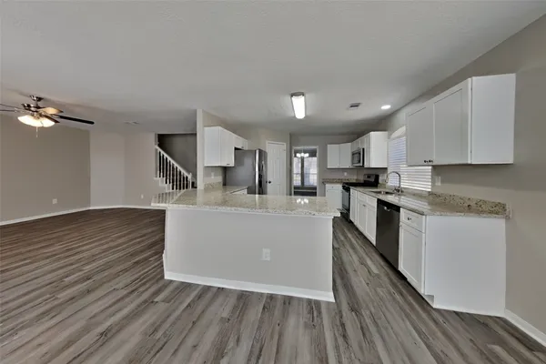 a large kitchen with cabinets wooden floor and stainless steel appliances