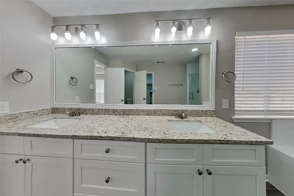 a bathroom with a granite countertop sink and a bathtub
