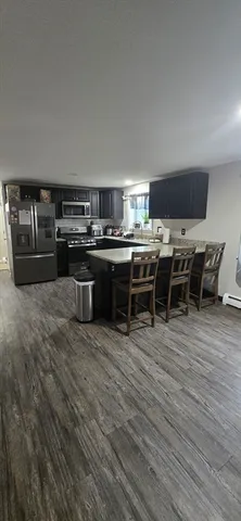 a view of a kitchen with stainless steel appliances a stove and wooden floor