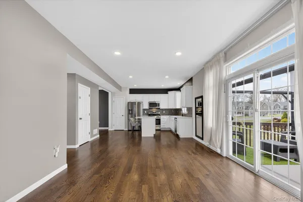 a view of a kitchen with kitchen island wooden floors and stainless steel appliances