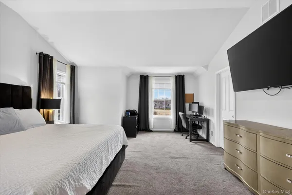 a bedroom with a bed and a flat tv screen on dresser