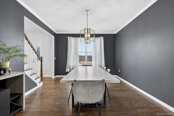 a dining room with wooden floor a chandelier a wooden table and chairs