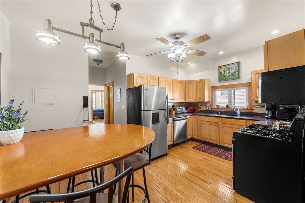 a kitchen with stainless steel appliances granite countertop a refrigerator a stove top oven a sink dishwasher and a dining table with wooden floor