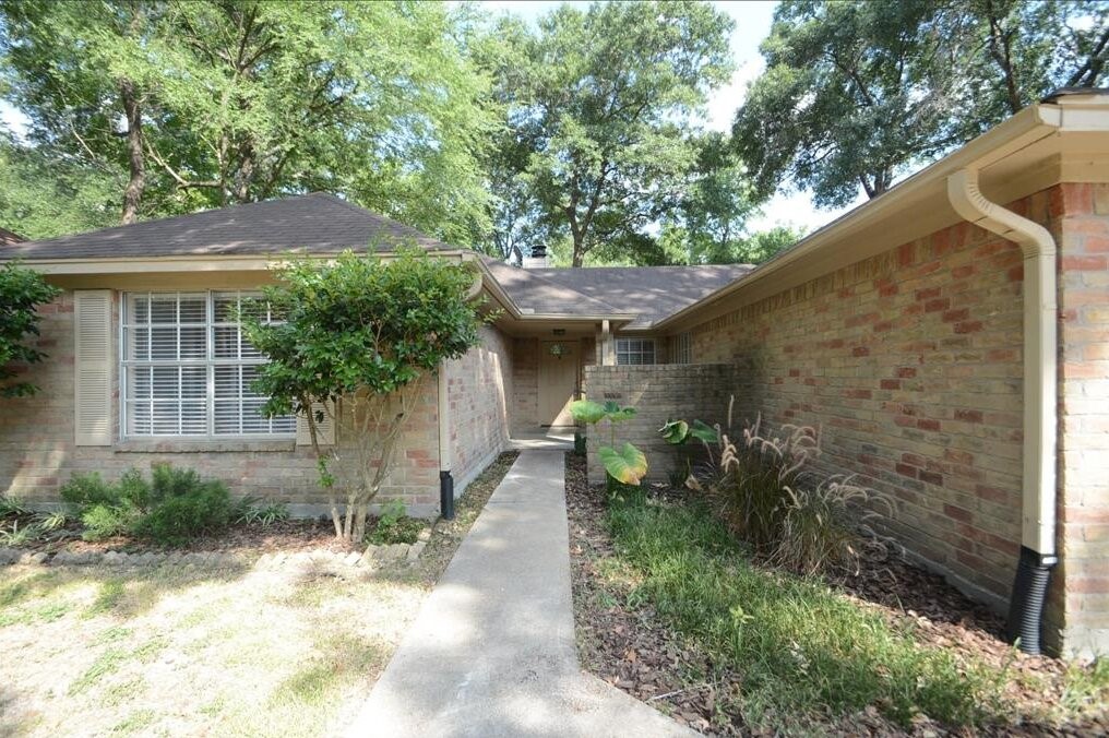 15 South Tallowberry Drive Spring, TX 77381 - Photo 3 of 26 Charming brick home entrance with a welcoming walkway, mature trees, and lush greenery.