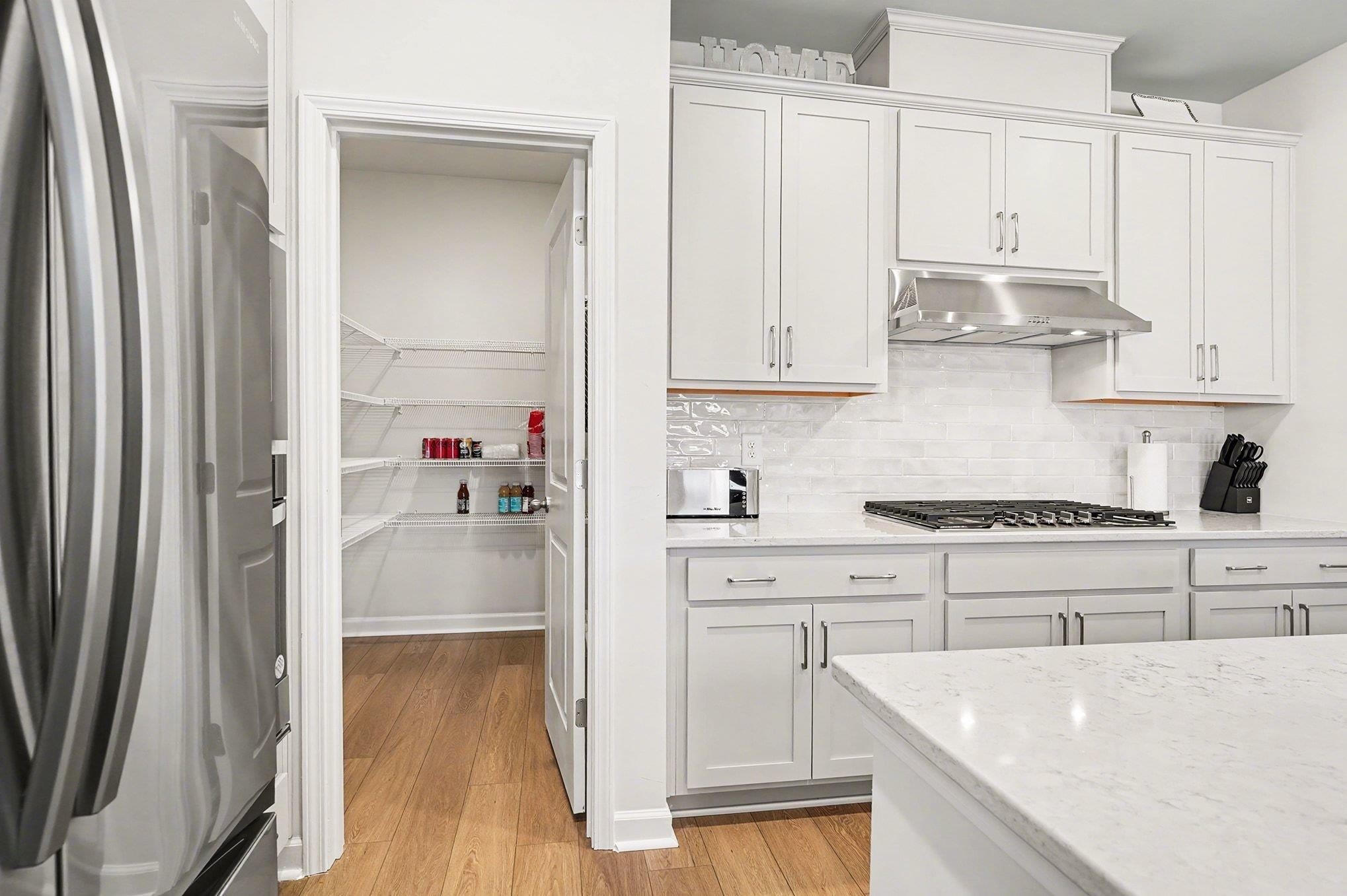 3005 Palma Way Myrtle Beach, SC 29579 - Photo 7 of 30 Kitchen featuring appliances with stainless steel finishes, white cabinetry, light wood-style floors, and light stone counters