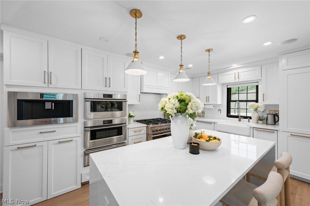 25870 Kennedy Ridge Road North Olmsted, OH 44070 - Photo 14 of 50 Kitchen featuring white shaker cabinetry, stainless steel double wall ovens, a built-in coffee system, and a large center island with a light-toned countertop