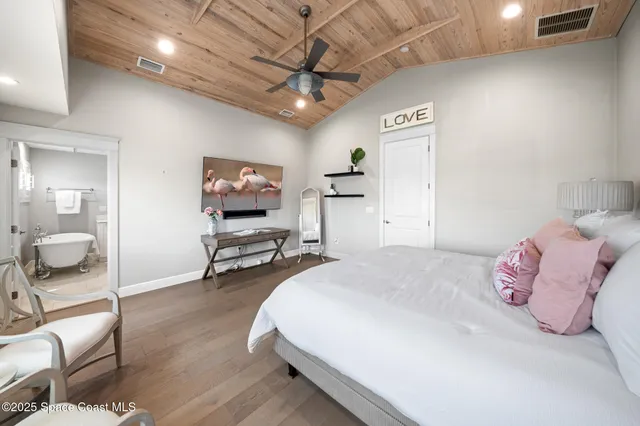 a spacious bedroom with a bed and a flat screen tv