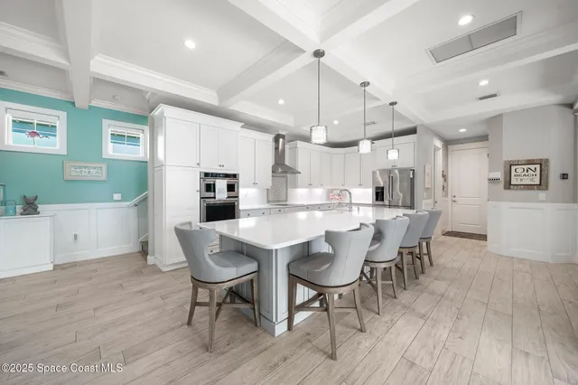 a kitchen with stainless steel appliances kitchen island granite countertop a dining table chairs and a refrigerator