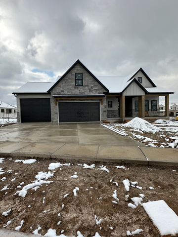 View of front of home with stone siding, board and batten siding, and driveway