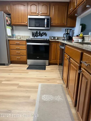 a kitchen with granite countertop wooden cabinets stainless steel appliances and a sink