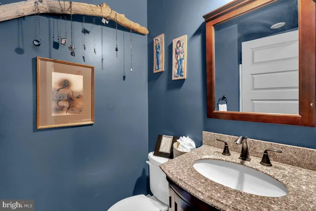 a bathroom with a granite countertop sink a toilet and a mirror