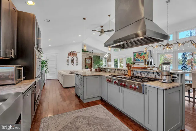 a kitchen with stainless steel appliances granite countertop a sink a stove and a wooden floors