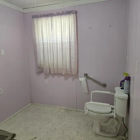a white toilet sitting in a bathroom next to a window