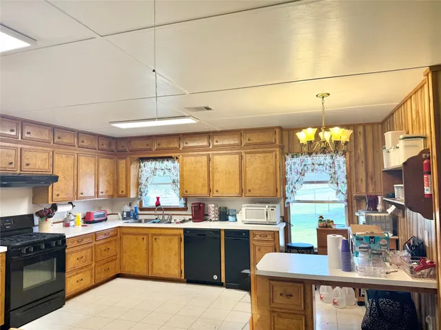 a kitchen with a sink appliances cabinets and a large window