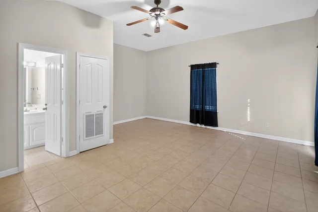 an empty room with ceiling fan and window