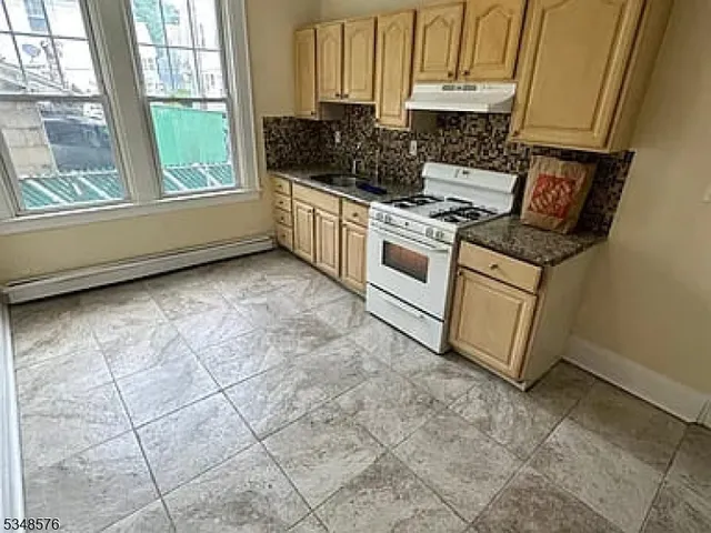 a kitchen with granite countertop a stove a sink and a white cabinets