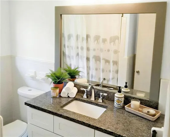 a bathroom with a granite countertop sink a toilet and a mirror