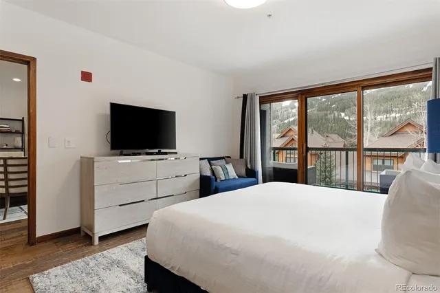 a bedroom with a large bed and a flat tv screen on dresser