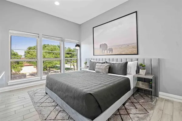 a bedroom with a bed painting and a large window