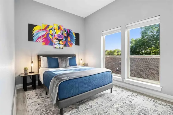 a bedroom with a bed a painting on the wall and a large window