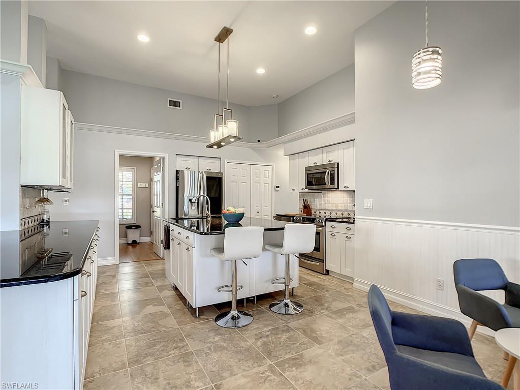 7858 Gardner Drive Naples, FL 34109 - Photo 14 of 35 a living room with furniture a flat screen tv and kitchen view