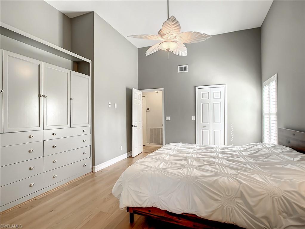 7858 Gardner Drive Naples, FL 34109 - Photo 22 of 35 a bedroom with a large bed and chandelier