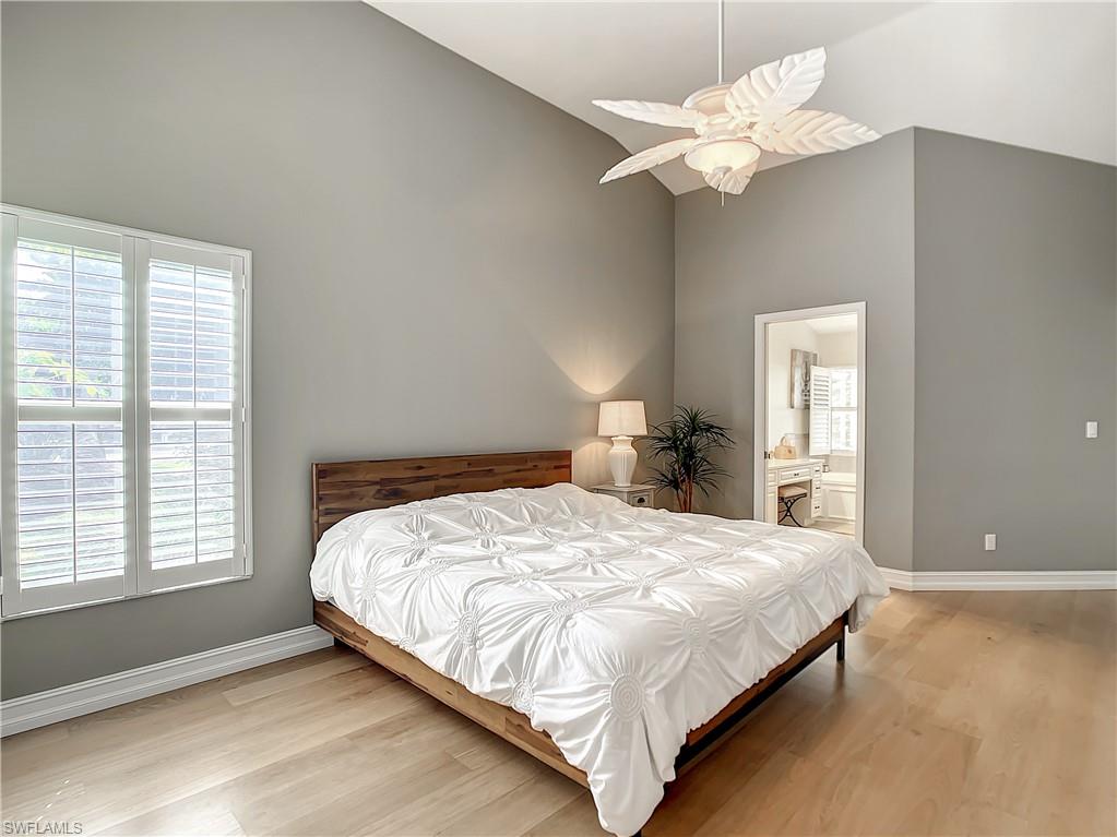 7858 Gardner Drive Naples, FL 34109 - Photo 23 of 35 a bedroom with a large bed chandelier and a window