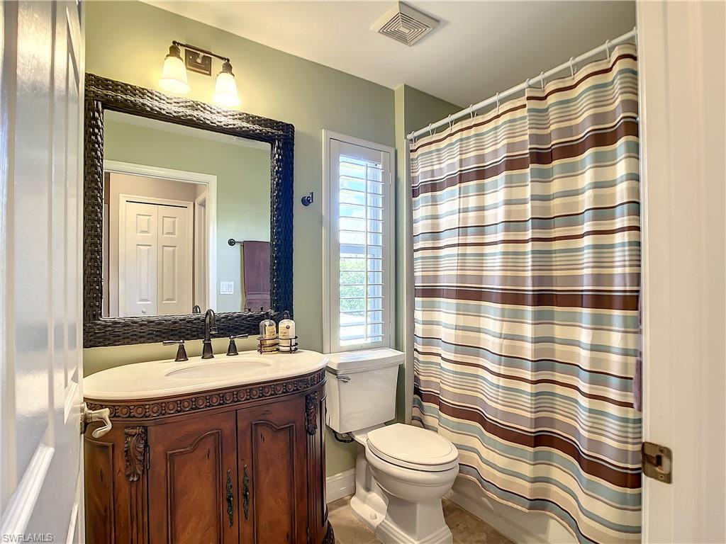 7858 Gardner Drive Naples, FL 34109 - Photo 31 of 35 a bathroom with a sink a toilet a mirror and shower curtain