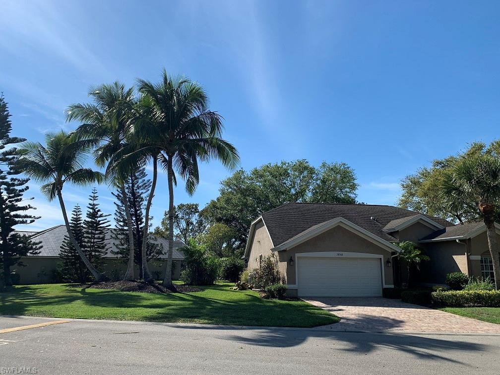 7858 Gardner Drive Naples, FL 34109 - Photo 5 of 35 a front view of a house with a garden and trees