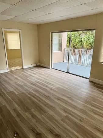 a view of an empty room with wooden floor and a window