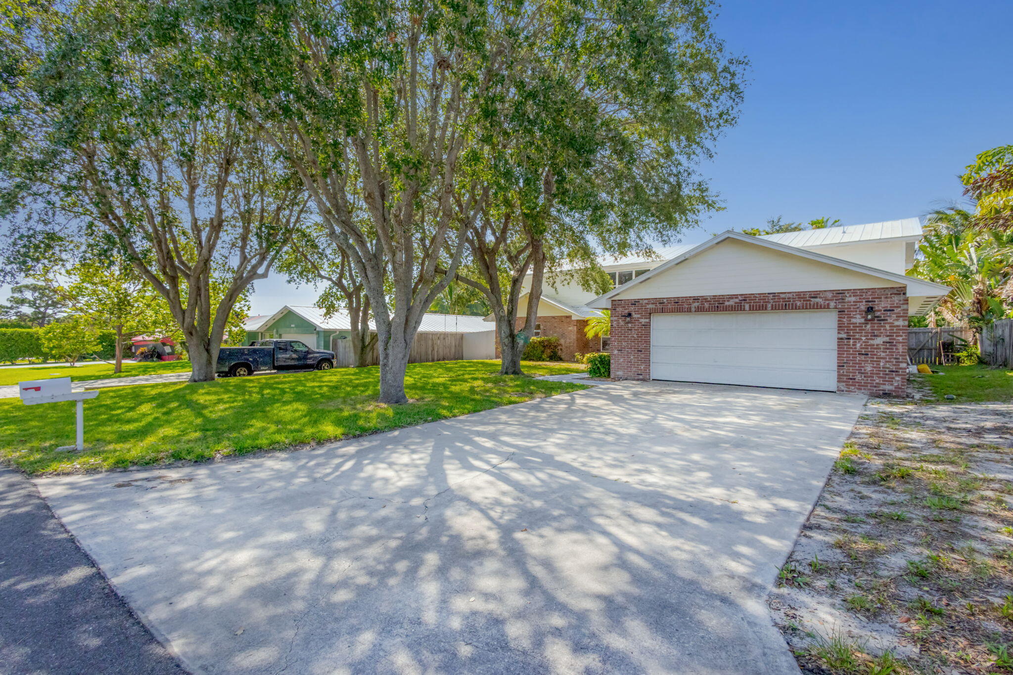 8888 Southeast Colony Street Hobe Sound, FL 33455 - Photo 2 of 69 a front view of a house with a yard and garage