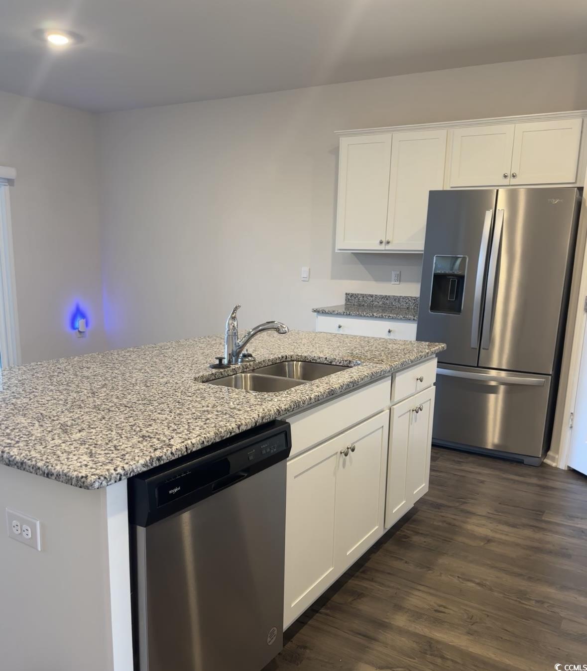 3789 Bells Lk Circle Longs, SC 29568 - Photo 4 of 26 Kitchen featuring appliances with stainless steel finishes, white cabinets, dark wood-style flooring, light stone countertops, and a kitchen island with sink