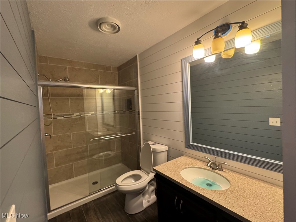 5880 Schramling Road Pierpont, OH 44082 - Photo 19 of 49 Bathroom featuring toilet, a stall shower, a textured ceiling, and wood finished floors