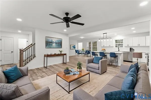 a living room with furniture kitchen view and a wooden floor